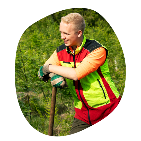 Forstmitarbeiter steht im Wald zwischen grünen Pflanzen