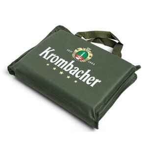 Grünes, quadratisches Stadionsitzkissen mit Tragegriff und weißem Schriftzug 'Krombacher' sowie Logo.