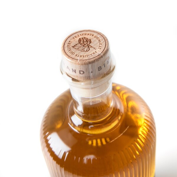 Flasche mit goldenem Bierbrand, Holzverschluss mit Prägung und Text 'PREMIERTE QUALITÄT' und Blätter-Motiv.