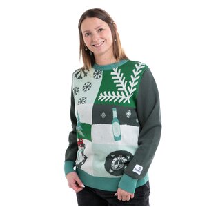 2437_krombachershop_Ugly_Sweater_Produkt_003 Person trägt einen grünen Pullover mit weißen Schneeflocken, Flaschenmotiv und Krombacher-Logo am Ärmel.