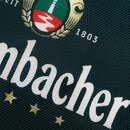 Nahaufnahme des Tabletts mit Krombacher-Logos mit drei goldenen Sternen und dem Gründungsjahr 1803 auf grünem Hintergrund mit Wabenmuster.