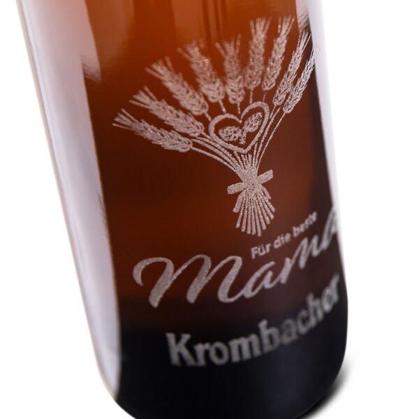 Braune Flasche 0,75L mit Gravur eines Weizenbündels, zwei ineinander verschlungenen Herzen und der Schrift 'Für die beste Mama' und Krombachr Logo.